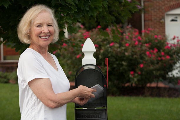 istock Smiling senior woman putting mail from her mailbox 510723315