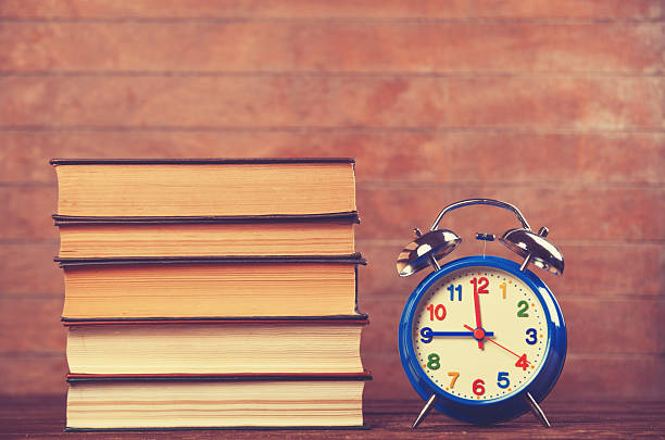 istock Alarm clock and books on wooden table. 510723443
