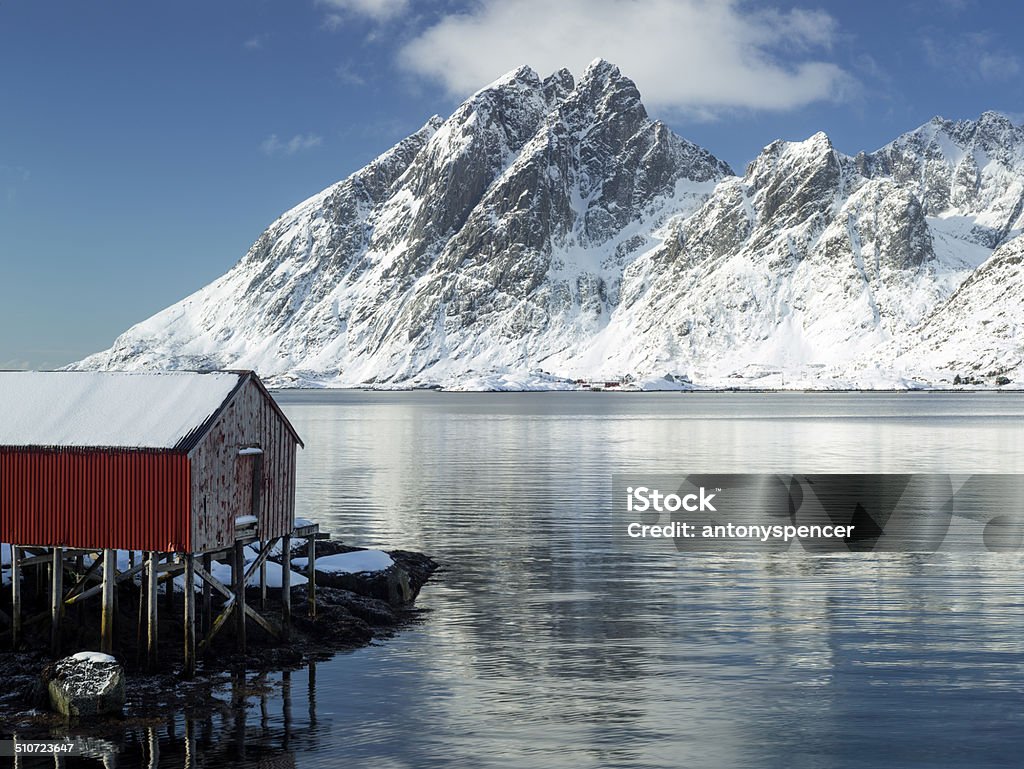 Lofoten islands rorbu and snow covered landscape A rorbu fisherman cabin and the wintry landscape backdrop of the Lofoten Island mountains, Arctic Norway Beach Stock Photo