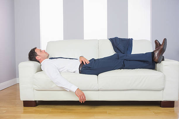 istock Tired handsome businessman lying on couch 510724879