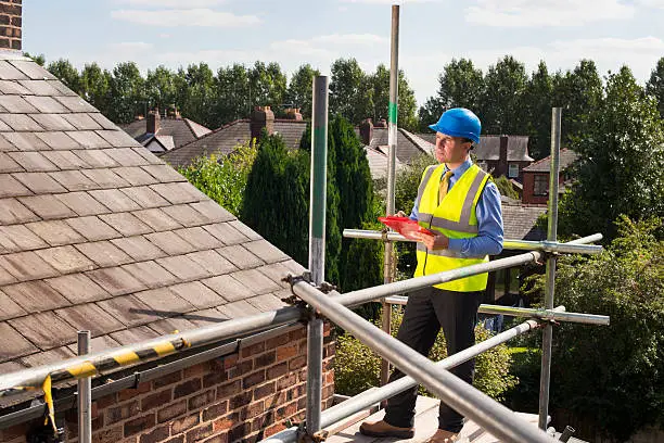 Photo of building inspector assesses slate roof condition