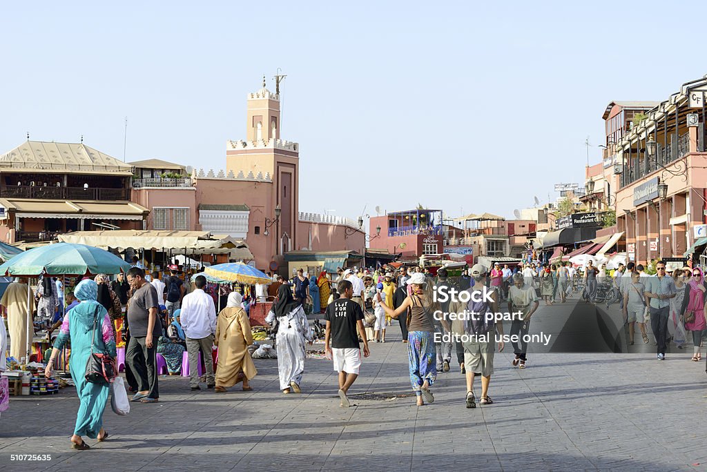 Djemaa el Fna - market place Marrakesh, Morocco - August 24, 2014: Tourists visiting Djemaa el Fna - market place in Marrakesh's medina quarter. Djemaa el Fna is a UNESCO world heritage site. Adult Stock Photo