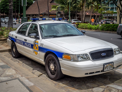 Waikiki, HI, USA -April 25, 2014: Honolulu Police Department police car parked in Waikiki on April 25, 2014. The white and blue cruiser is parked on kalakaua Avenue.