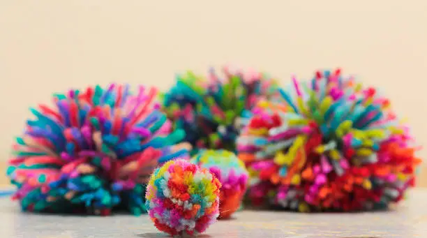 Home made rainbow pom-poms sitting in a cluster