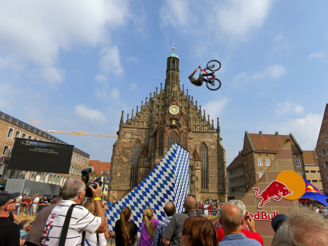 Nuremberg, Germany - September 5, 2014: A cyclist is making a somersault with his bicycle in front of the famous gothic Frauenkirche at the marketplace  in Nuremberg. The freeride event 