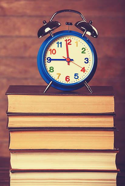 istock Alarm clock and books on wooden table. 510740335