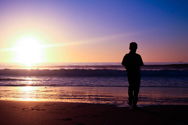 istock Lonely boy on the beach with sunrise - Silhouette 510767489