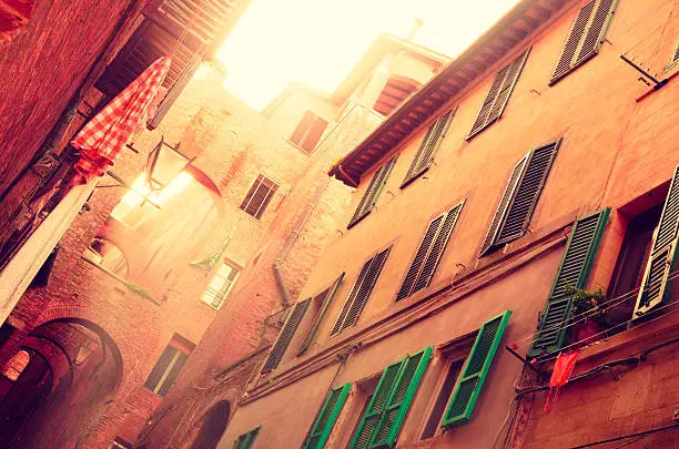 Toscan old street in orange luminous warm tones in the medieval city of Siena.