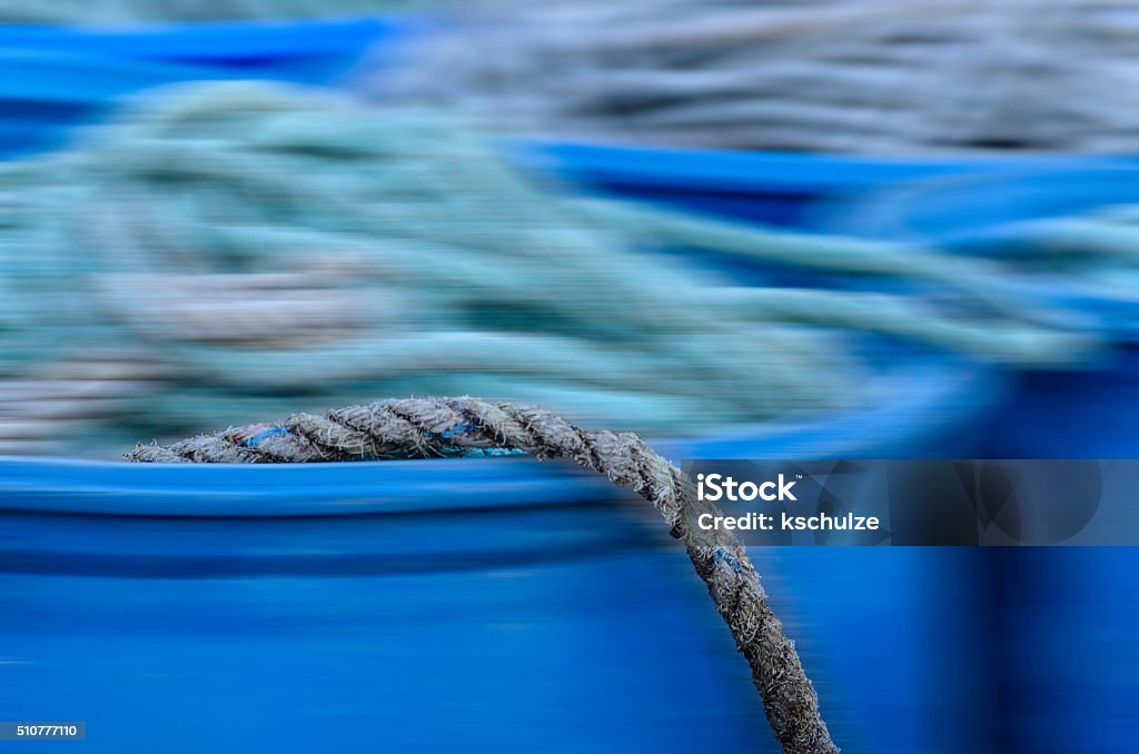 Out of here Motion blur of commercial fishermen's rope in blue barrels, with unblurred part of one rope hanging over the lip of barrel in foreground Abundance Stock Photo