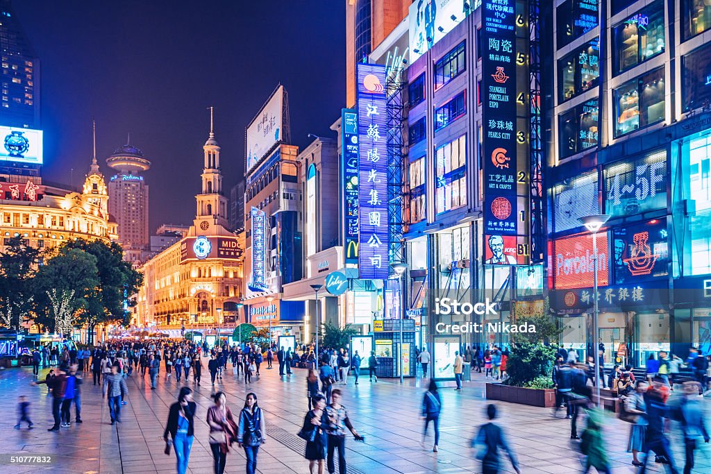 busy Shoppping Street in Shanghai, China Crowds walk below neon signs on Nanjing Road. The street is the main shopping district of the city and one of the world's busiest shopping districts.  China - East Asia Stock Photo