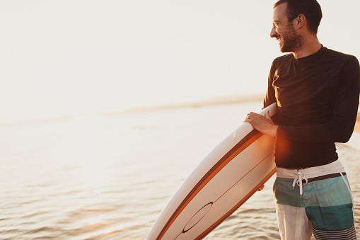 Portrait of a surfer, holding his board after a good surfing day