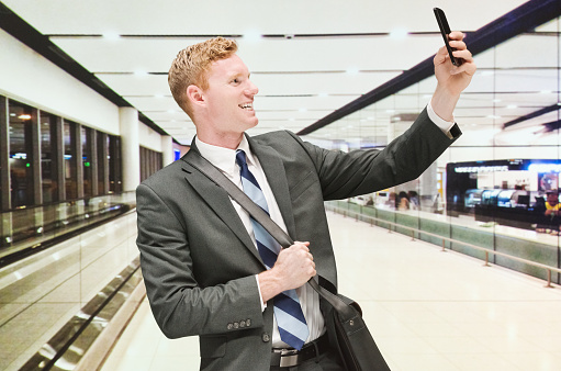 Smiling businessman taking a selfie in airporthttp://www.twodozendesign.info/i/1.png