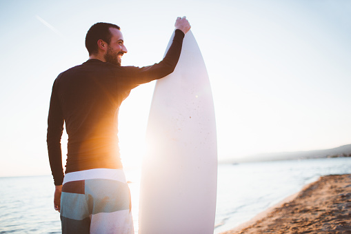 Portrait of a surfer, holding his board after a good surfing day