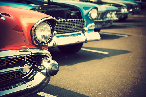 Photograph of classic cars with close-up on headlights parked in a row.