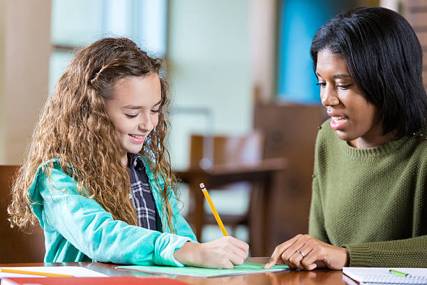 istock Elementary age little girl doing homework with help of tutor 510790946