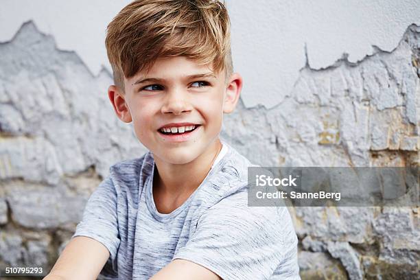 Young Boy Leaning Against Wall Smiling Stock Photo - Download Image Now - 6-7 Years, Boys, Brick Wall