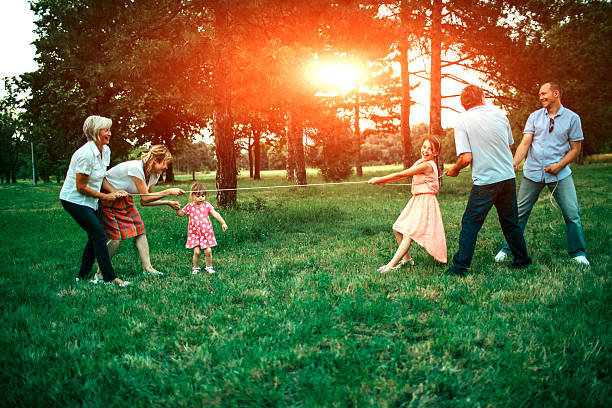 Three generations family having fun playing tug of wars outdoors on picnic. They are enjoy spending time together.