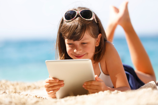 LIttle girl using digital tablet on the beach