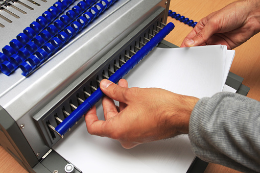 Gray Binding machine with man who works on it