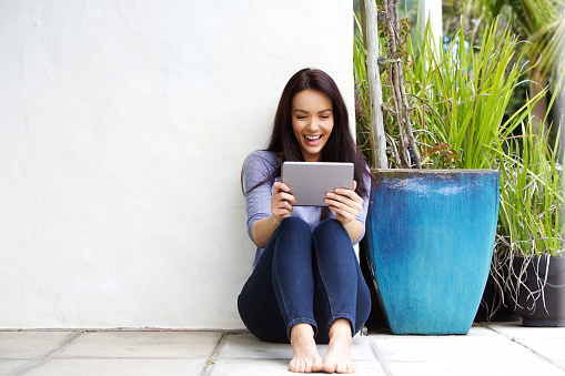 Portrait of happy young woman looking at a digital tablet and smiling