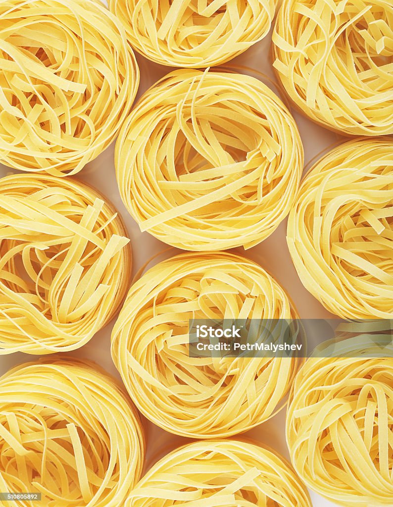 Raw Nest Pasta raw pasta tagliatelle nest on table, top view background Pasta Stock Photo