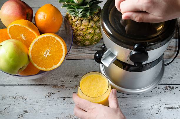 man preparing fresh orange juice. fruits in background - 榨汁機 個照片及圖片檔