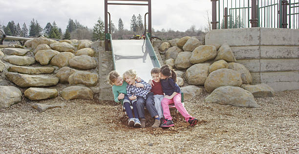 istock Young children laughing together on slide at park 510846136