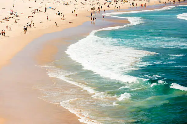 Summer at the beach and ocean, Bondi Beach is crowded with a large number of beachgoers on a hot Sunday afternoon, full frame horizontal composition with copy space