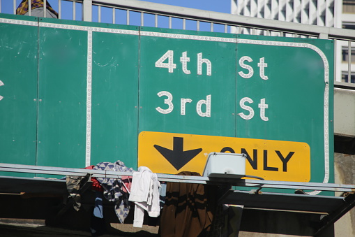 This is the 4th and 3rd street exit sign off the 101 Freeway in LA. There is a guy on the overpass who started throwing (presumably) his clothes onto the the overpass sign.