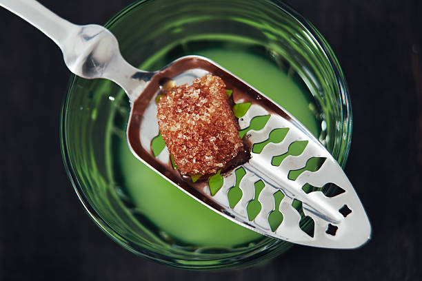 Absinthe With Spoon and Sugar Cube Glass of absinthe with water poured over a sugar cube. Includes absinthe spoon. absinthe spoon stock pictures, royalty-free photos & images