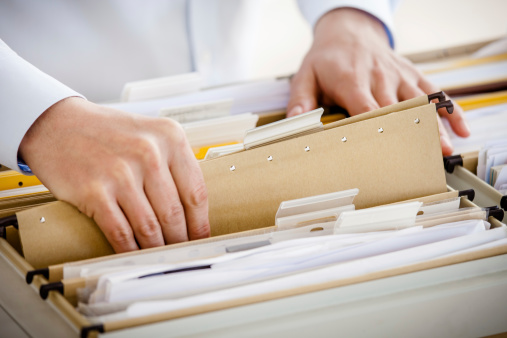 Close-up of hands searching in a file cabinet