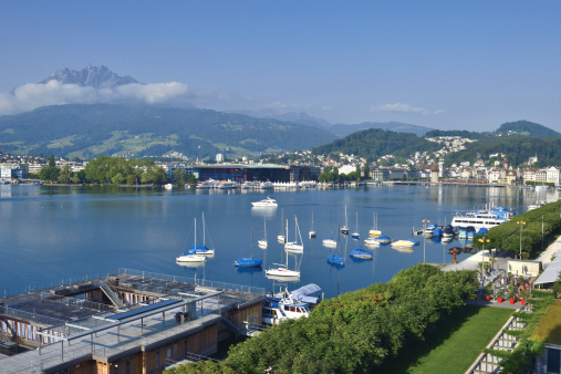Panoramic view of Lake Lucerne, green alpine meadows blooming in spring time and the Alps mountains range with Mount Pilatus, Switzerland