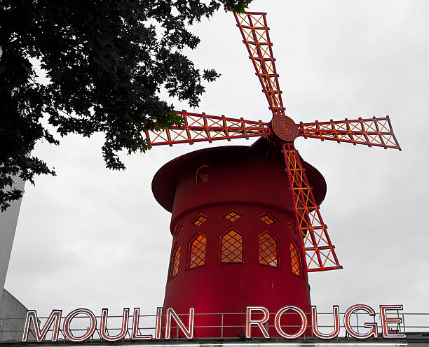 Moulin Rouge Paris, France - June 1, 2014:  Le Moulin Rouge(Red Mill) is a cabaret built in 1889. It's situated near Montmartre in the district of Pigalle in the 18th arrondissement of Paris. On this picture le moulin rouge is in front of grey sky. place pigalle stock pictures, royalty-free photos & images