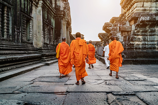 Siem Reap, Cambodia - December 25, 2015: Group of cambodian buddhist monks in their typical traditional orange robes walking inside the ancient famous Angkor Wat Temple. Angkor Wat, Siem Reap, Cambodia, Asia.