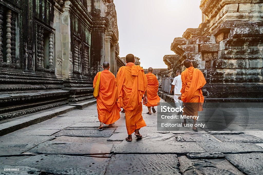 Buddhist Monks in Angkor Wat Cambodia Siem Reap, Cambodia - December 25, 2015: Group of cambodian buddhist monks in their typical traditional orange robes walking inside the ancient famous Angkor Wat Temple. Angkor Wat, Siem Reap, Cambodia, Asia. Cambodia Stock Photo
