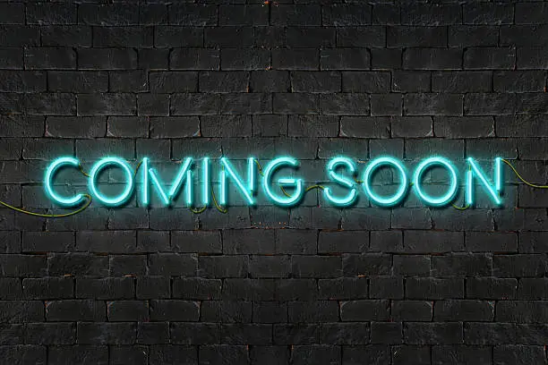 "COMING SOON" neon sign shining on black brick wall,Business concept.