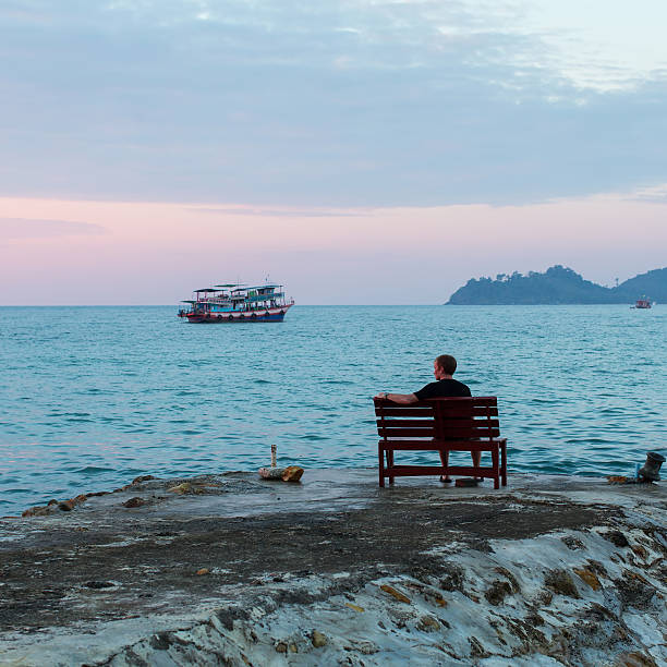 istock Lone young man sits on a bench at the seaside. 510870736