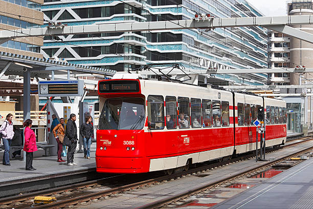 The Hague, The Netherlands - May 16, 2012: Commuters wait to board a Route 6 tram to Leyenburg at one of the two tram stops at The Hague Central Station (Den Haag Centraal Station).  The railway station is a public transport hub that features convenient access between trains, trams and buses.  There are two tram stations, one on a platform above the rail tracks and one at track level outside the station entrance.  The bus station is also above the rail tracks and connected to the nearby Prins Bernhardviaduct main road.