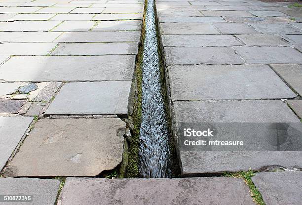 Small Stream Rill Running Down Centre Of Flagstone Paved Street Stock Photo - Download Image Now