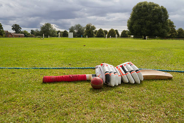 Cricket bat and gloves on English village green. stock photo