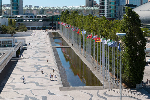 Lisbon, Portugal - August 07, 2014: Visitors comming in and out of the Vasco da Gama Shopping, Sao Rafael Tower in the back and Homem-Sol (Sun-Man) Sculpture. Parque das Nacoes.