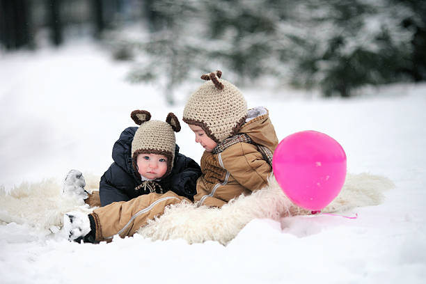 dois irmãos em idêntica tampas de descanso - balloon child winter snow imagens e fotografias de stock