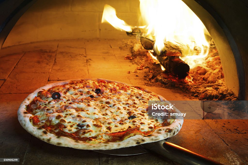 Firewood oven pizza Close up pizza in firewood oven with flame behind Pizza Stock Photo