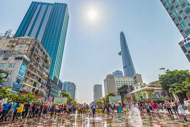 Ho Chi Minh City, Vietnam - 10 February 2024: Vietnamese celebrate Tet, the Chinese New Year of the Dragon, in Flower and Book Street. People take pictures and selfies in front of flower arrangements and dragon sculptures.