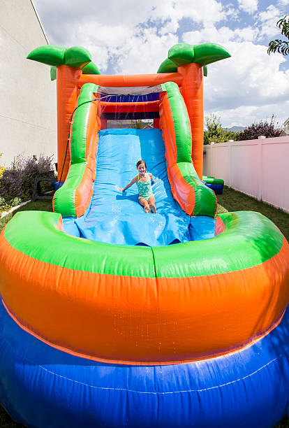 sorridente menina jogando no slide ao ar livre salto assembleia insufláveis - house bouncing multi colored outdoors imagens e fotografias de stock