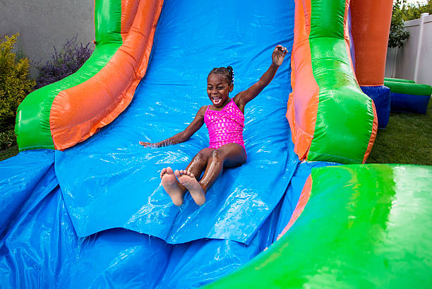 szczęśliwy mała dziewczynka z nadmuchiwane przesuwając w dół bounce dom - inflatable slide sliding child zdjęcia i obrazy z banku zdjęć