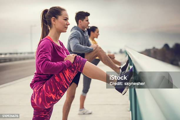 Young Athletes Stretching Their Legs Outdoors Before Exercising Stock Photo - Download Image Now