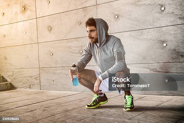 Athlete Crouched With A Sport Drink Stock Photo - Download Image Now - Men, Drinking, Sport Drink