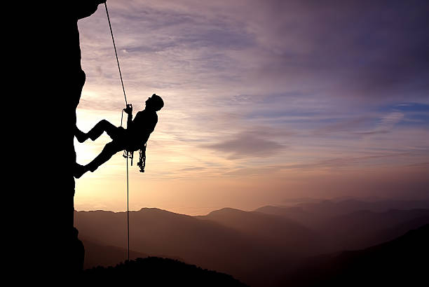silueta de escalador de roca al anochecer - risk high up sport outdoors fotografías e imágenes de stock