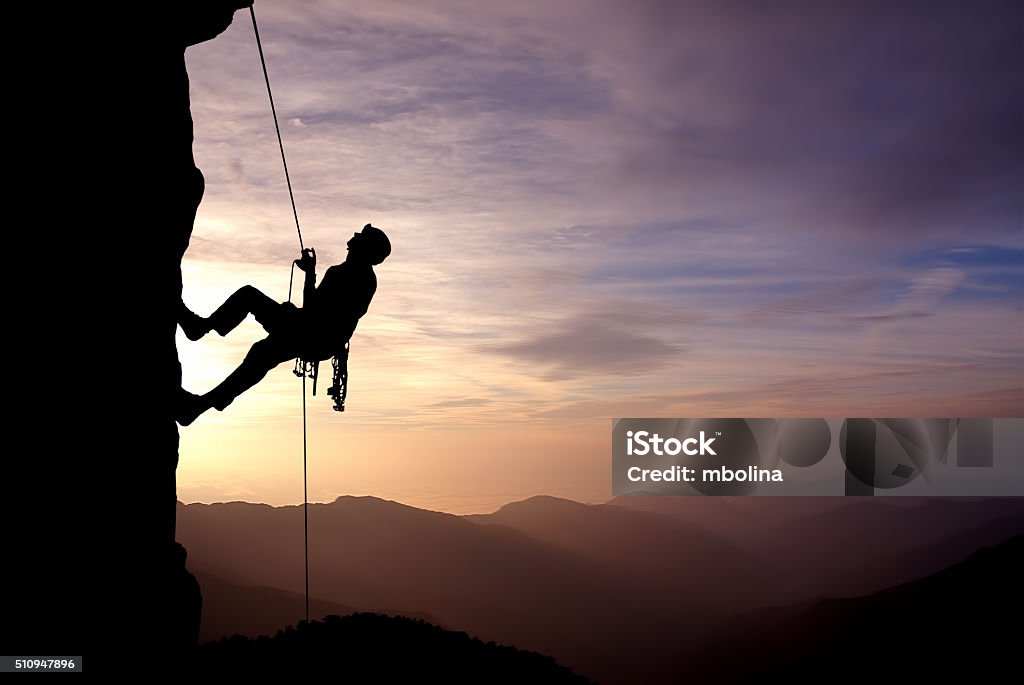 Silhouette of Rock Climber at Sunset Silhouette of a climber on a vertical wall over beautiful sunset Persistence Stock Photo